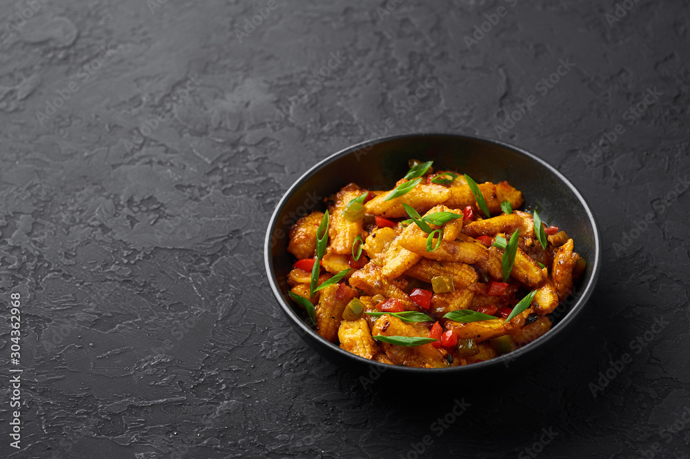 Baby Corn Manchurian dry looks like Schezwan Baby Corn in black bowl at dark slate background. Baby Corn Manchurian - is indo chinese cuisine dish with deep fried corn, bell peppers, sauce and onion. Baby Corn Manchurian dry looks like Schezwan Baby Corn in black bowl at dark slate background. Baby Corn Manchurian - is indo chinese cuisine dish with deep fried corn, bell peppers, sauce and onion.