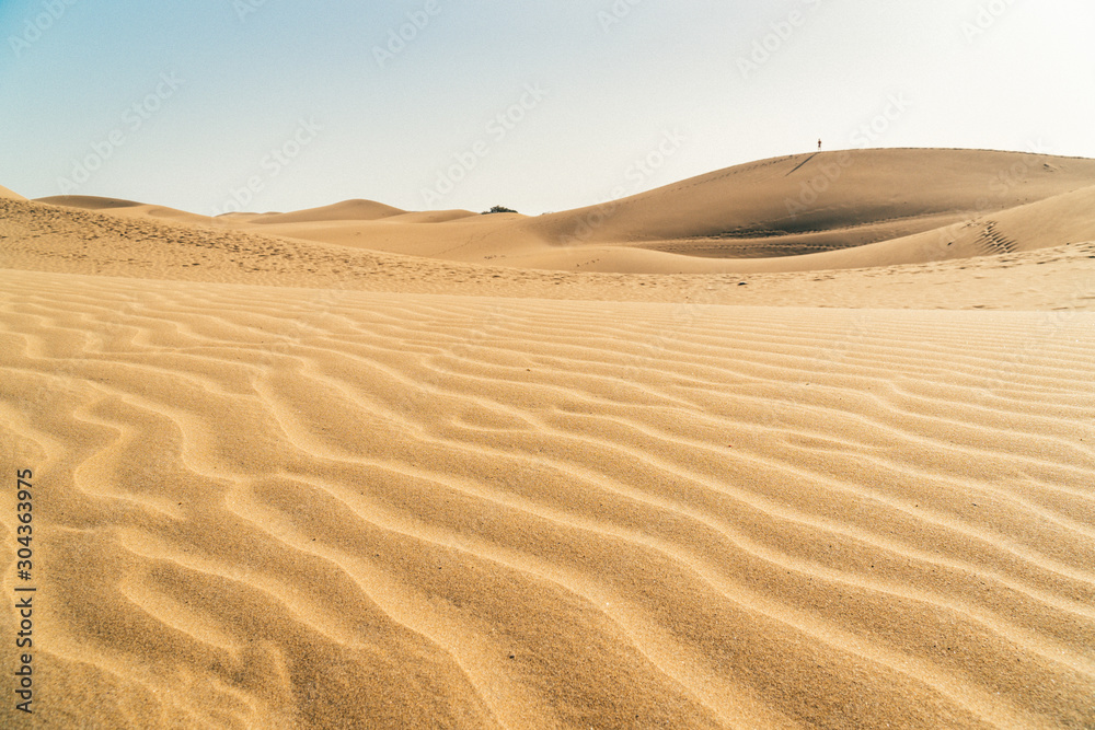Low shot sand dunes in Maspalomas, Las Palmas of Gran canaria, tropical Canary island in Atlantic ocean, Spain, people in distance