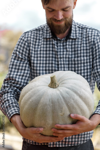 big pumpkin in the hands. Bearded man holding a pumpkin photo