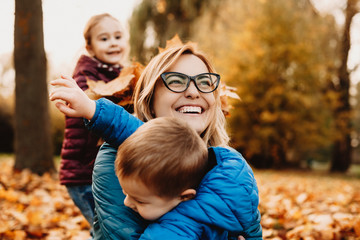 Close up of a amazing young mother laughing while playing with her kids outdoor. Lovely mother hugging her little son laughing in the park.