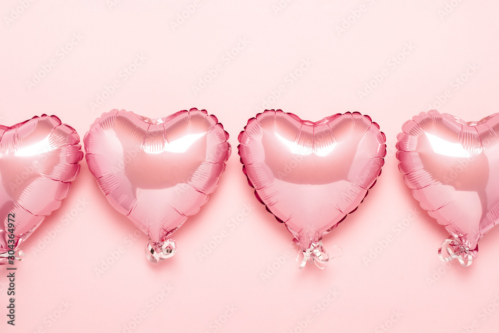 Pink air balloons in the shape of a heart on a pink background. Concept for Valentine's day, decoration, wedding, invitation or photo zone. Foil balls. Flat lay, top view