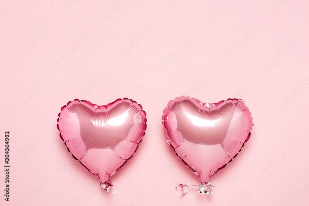 Two pink air balloons in the shape of a heart on a pink background. Concept Valentine's Day, Wedding Decoration. Foil balls. Flat lay, top view