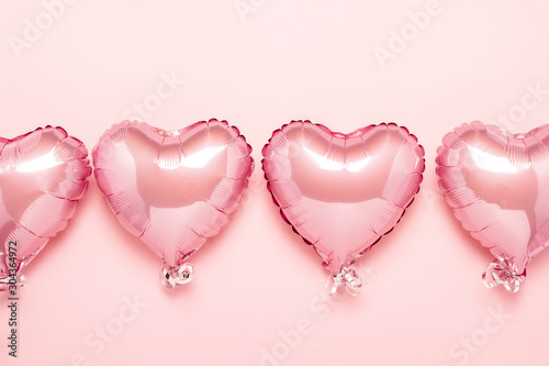 Pink air balloons in the shape of a heart on a pink background. Concept for Valentine's day, decoration, wedding, invitation or photo zone. Foil balls. Flat lay, top view