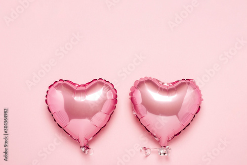 Two pink air balloons in the shape of a heart on a pink background. Concept Valentine's Day, Wedding Decoration. Foil balls. Flat lay, top view