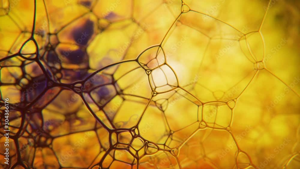 Soap foam filled with blue ink popping bubbles against yellow background. Abstract coloured structure. Soap foam filled with blue ink popping bubbles against yellow background. Abstract coloured structure.