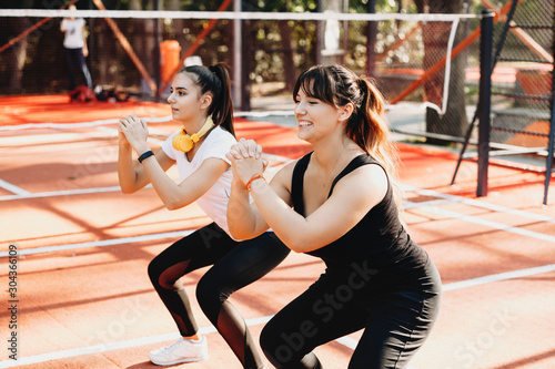 Lovely young plus size female doing lose weight exercise with her fit girlfriend outdoor ina sport park .