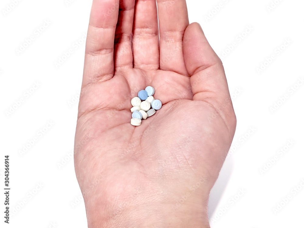 Hand holding a handful of multi-colored birth control pills against a white background Hand holding a handful of multi-colored birth control pills against a white background