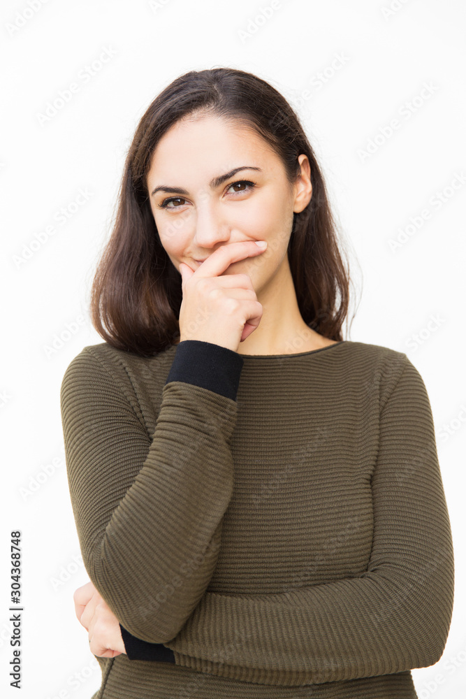 Cheerful Latin woman covering mouth with hand and hiding smile. Young woman in casual standing isolated over white background. Keeping secret concept Cheerful Latin woman covering mouth with hand and hiding smile. Young woman in casual standing isolated over white background. Keeping secret concept
