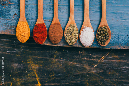 flat lay of colorful spices in spoons on wooden table