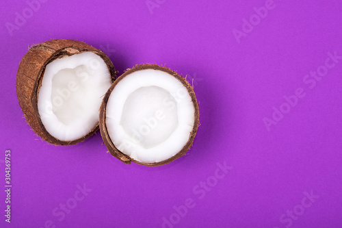 Top view of half ripe coconut on violet purple background. Summer concept. Minimalism. Place for text
