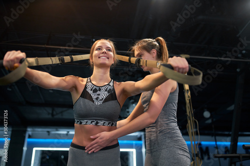 Two athletic women in sportswear training with elastic bands