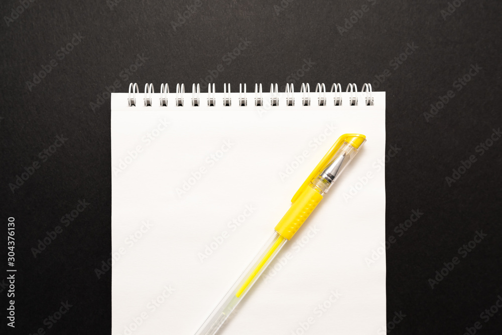 school white notebook with pen on black background school white notebook with pen on black background