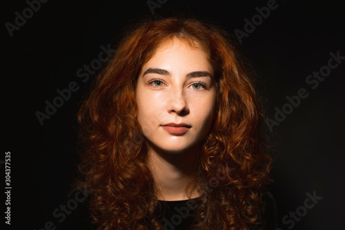 Fototapeta Naklejka Na Ścianę i Meble -  Portrait of young woman, with ginger and curly hair, over dark isoalted background