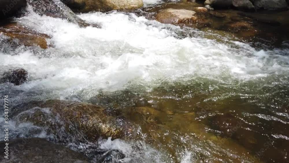 motion of a small waterfall in a deep forest from the water to the top of waterfall in summer season. Beautiful small topical waterfall. A small lake into which falls a waterfall in Thailand motion of a small waterfall in a deep forest from the water to the top of waterfall in summer season. Beautiful small topical waterfall. A small lake into which falls a waterfall in Thailand