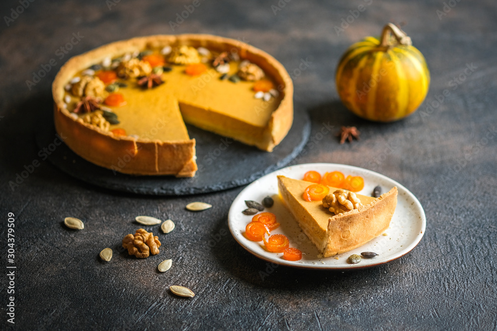 Traditional american homemade holiday pumpkin pie on a dark background with pumpkins. Traditional american homemade holiday pumpkin pie on a dark background with pumpkins.