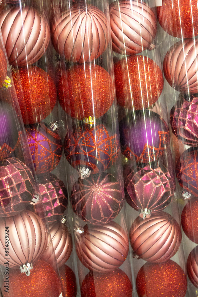 New Year's shiny toys, decor, red, purple, pink Christmas balls in transparent plastic packaging are sold in the Christmas market. Background, Christmas sales concept.
