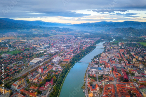 Aerial view of Maribor city in Slovenia on the banks of Drava river. Scenic landscape with buildings, water, mountains and blue cloudy sky, travel background, Lower Styria region photo