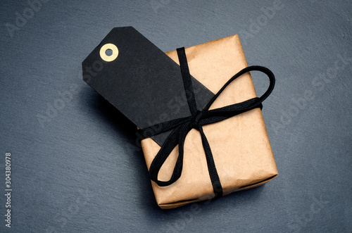 Black background and price label. Black Friday. Sales concept. Copy space. Black paper label and gift box from recycled brown paper. Black Friday sale concept. close up. Zero Wast.