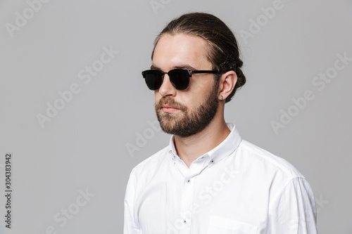 Man posing isolated over grey wall background wearing sunglasses.