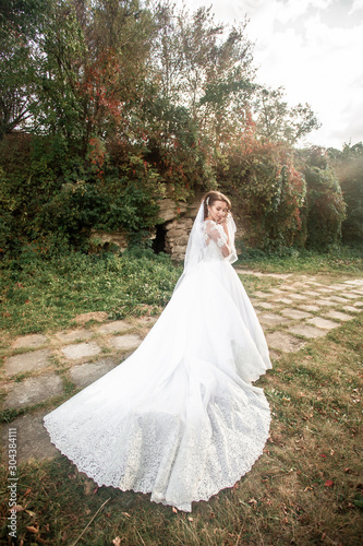 fairy-tale princess in light dress on wide path and walks towards wind. Stylish bride on a walk