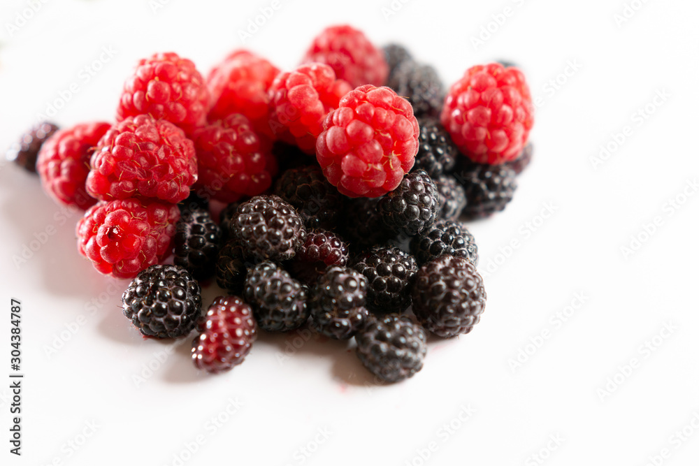 Fragrant sweet red and black raspberries on a white background. Fragrant sweet red and black raspberries on a white background.