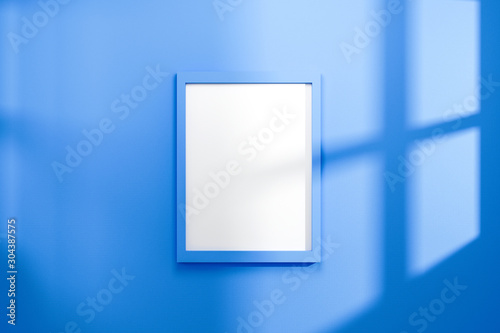Fototapeta Naklejka Na Ścianę i Meble -  Empty frame on vivid blue wall background with natural light of window. Display of showing exhibition. Realistic 3D render.