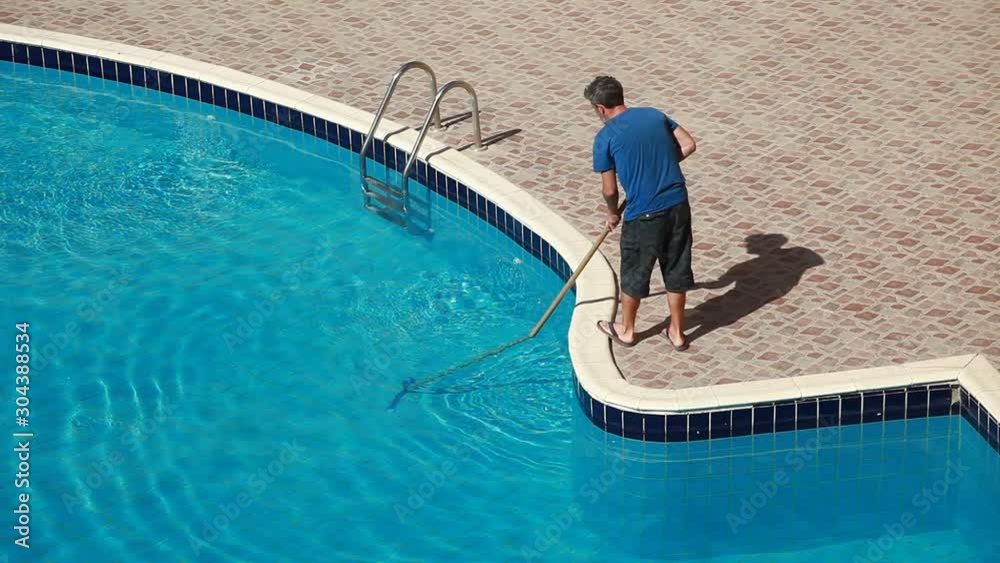 Male worker cleaning outdoor pool with scoop net