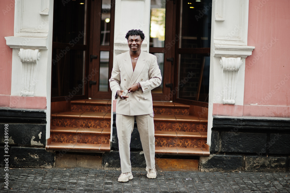 Stylish afro man in beige old school suit. Fashionable young African male in casual jacket on bare torso.