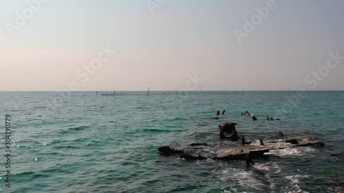 Paning revealing aerial drone shot of a shipwreck that extends into the ocean over a golden sandy shore and the blue sea of Mediterranean sea close to Thessaloniki, Greece in Epanomi photo