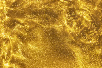 Abstract elegant, detailed gold glitter particles flow with shallow depth of field underwater. Holiday magic shimmering luxury background. Festive sparkles and lights. de-focused.