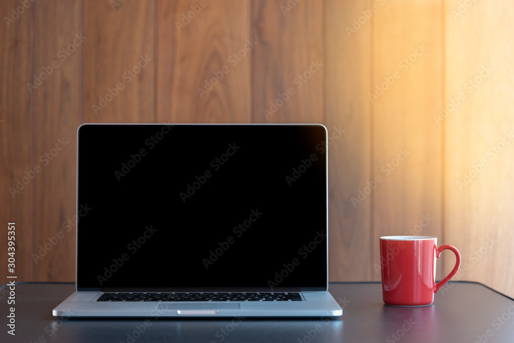 workstation using a laptop and holding a cup of coffee with wood background