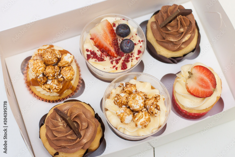 Box of assorted cupcakes with cream cheese vanilla and chocolate frosting, fresh strawberries, raspberries, blueberries and popcorn decoration. Box of assorted cupcakes with cream cheese vanilla and chocolate frosting, fresh strawberries, raspberries, blueberries and popcorn decoration.