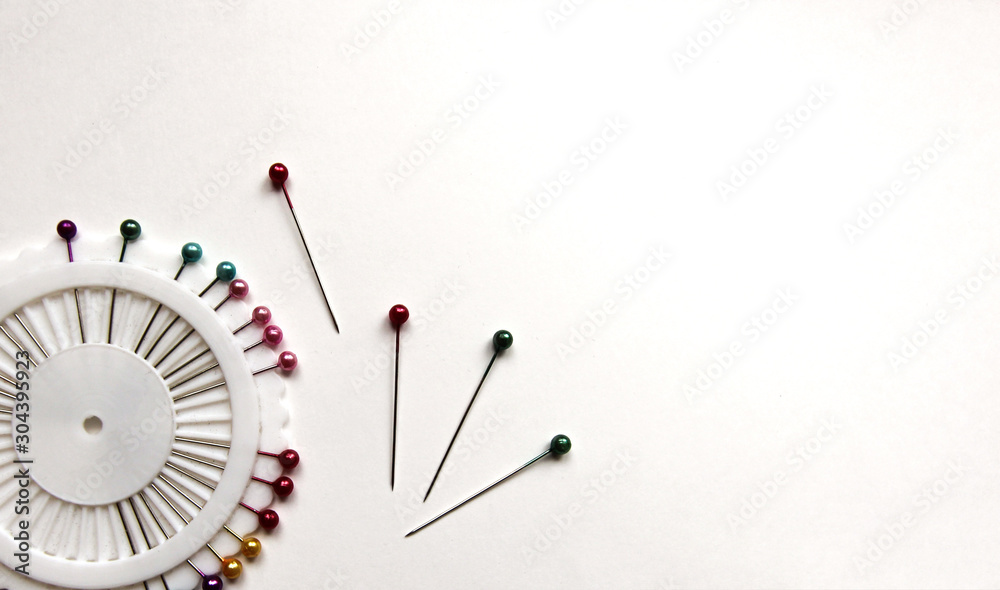 Set of sewing pins with colored beads in an white organizer on a white isolated background. Place for text. Set of sewing pins with colored beads in an white organizer on a white isolated background. Place for text.