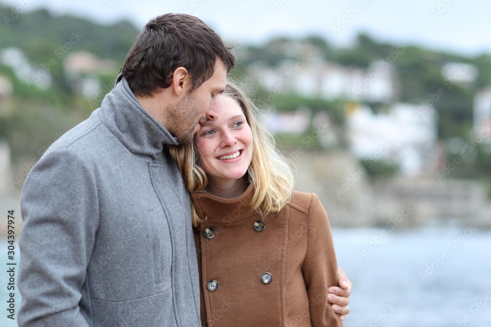 Happy couple flirting walking on the beach in winter Happy couple flirting walking on the beach in winter