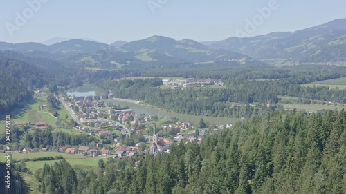 Aerial pan drone shot over town of Dravograd in lush green valley below photo