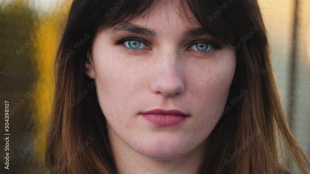Close up portrait of woman with beautiful blue eyes, long brown hair look at camera. With serious face, natural skin and less make up. Close up portrait of woman with beautiful blue eyes, long brown hair look at camera. With serious face, natural skin and less make up.
