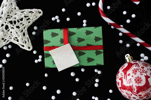 Christmas decoration with candy stick, handmade ornament ball, white star and gift box on black background.