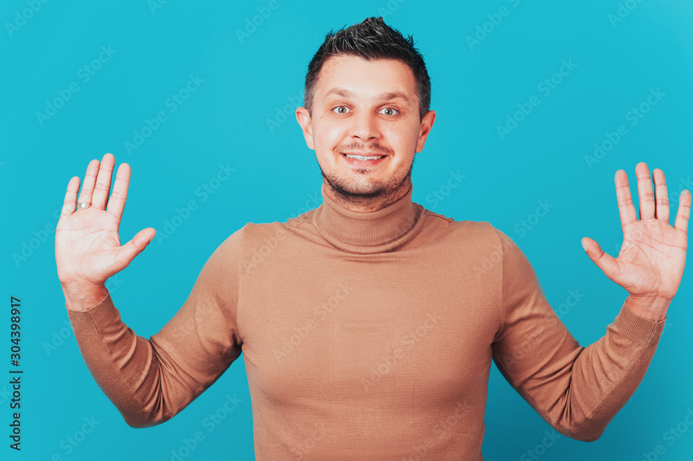 Merry man spreads palms, has joyous expression, white teeth, makes decision, gets unexpected offer. young male stands with palms outstretched in camera, looks surprisingly at camera. Merry man spreads palms, has joyous expression, white teeth, makes decision, gets unexpected offer. young male stands with palms outstretched in camera, looks surprisingly at camera.