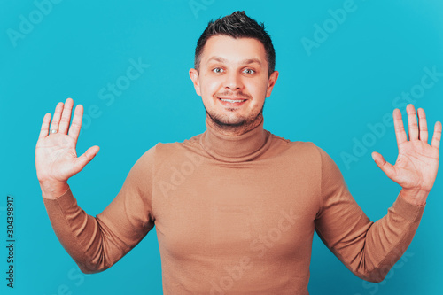 Merry man spreads palms, has joyous expression, white teeth, makes decision, gets unexpected offer. young male stands with palms outstretched in camera, looks surprisingly at camera.