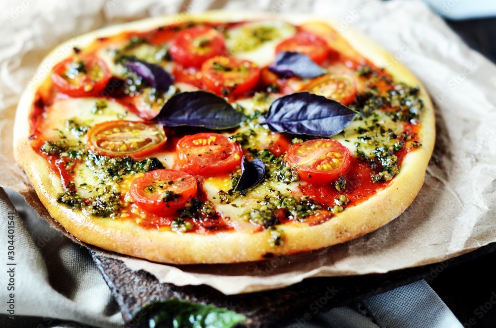 Pizza margarita with pesto on a dark wooden background Pizza margarita with pesto on a dark wooden background
