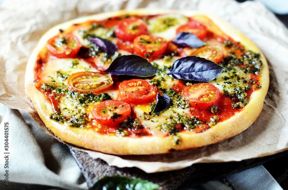 Pizza margarita with pesto on a dark wooden background Pizza margarita with pesto on a dark wooden background