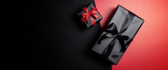 black gift box with black ribbons isolated on black background