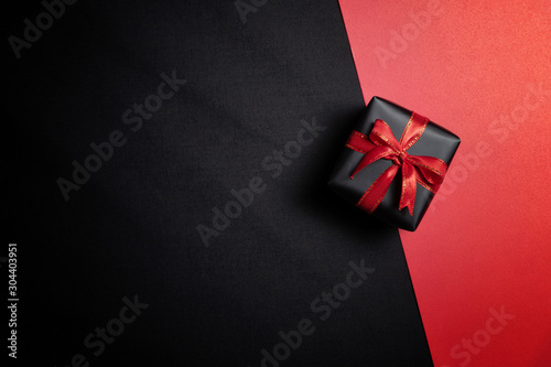 black gift box with black ribbons isolated on black background