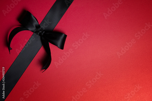 Top view of black ribbon on red background with free copy space for text.