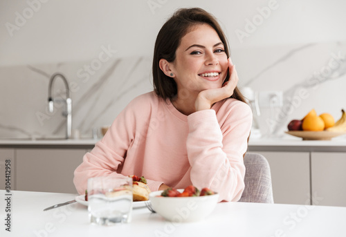 Beautiful smiling young girl having tasty healthy breakfast
