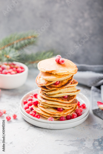 Homemade pancake or hot cake stacked on white plate with berry on grey stone Background, Christmas Dessert.