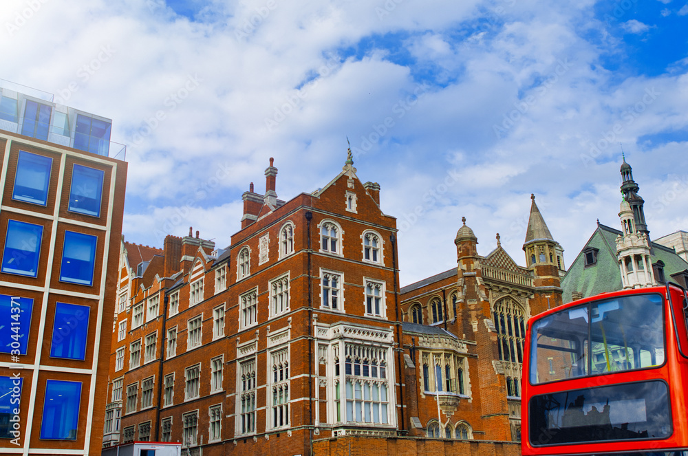 Red Bus along London street in the middle of old buildings, UK