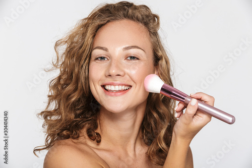Картината върху платно Image of beautiful half-naked woman smiling and using makeup brush