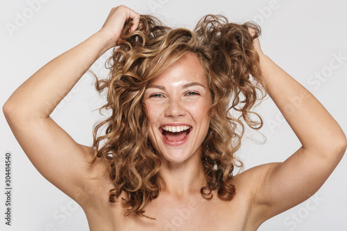 Image of laughing half-naked woman making fun with her curly hair photo