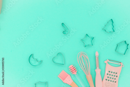 Flatlay  pink kitchen utensils on neo mint background. Greater, whisk and iron cooking form. Top horizontal view copyspace love cookong concept photo